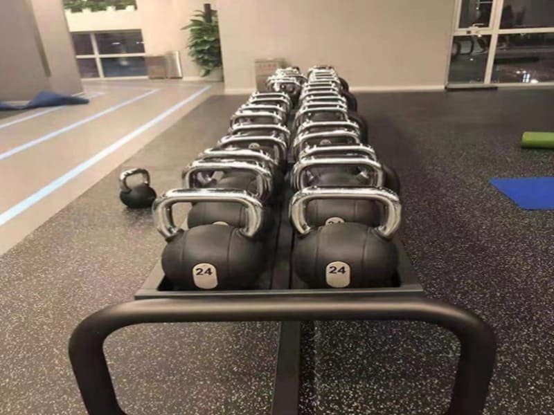An engineer using a level to check the flatness of a concrete subfloor before gym flooring installation